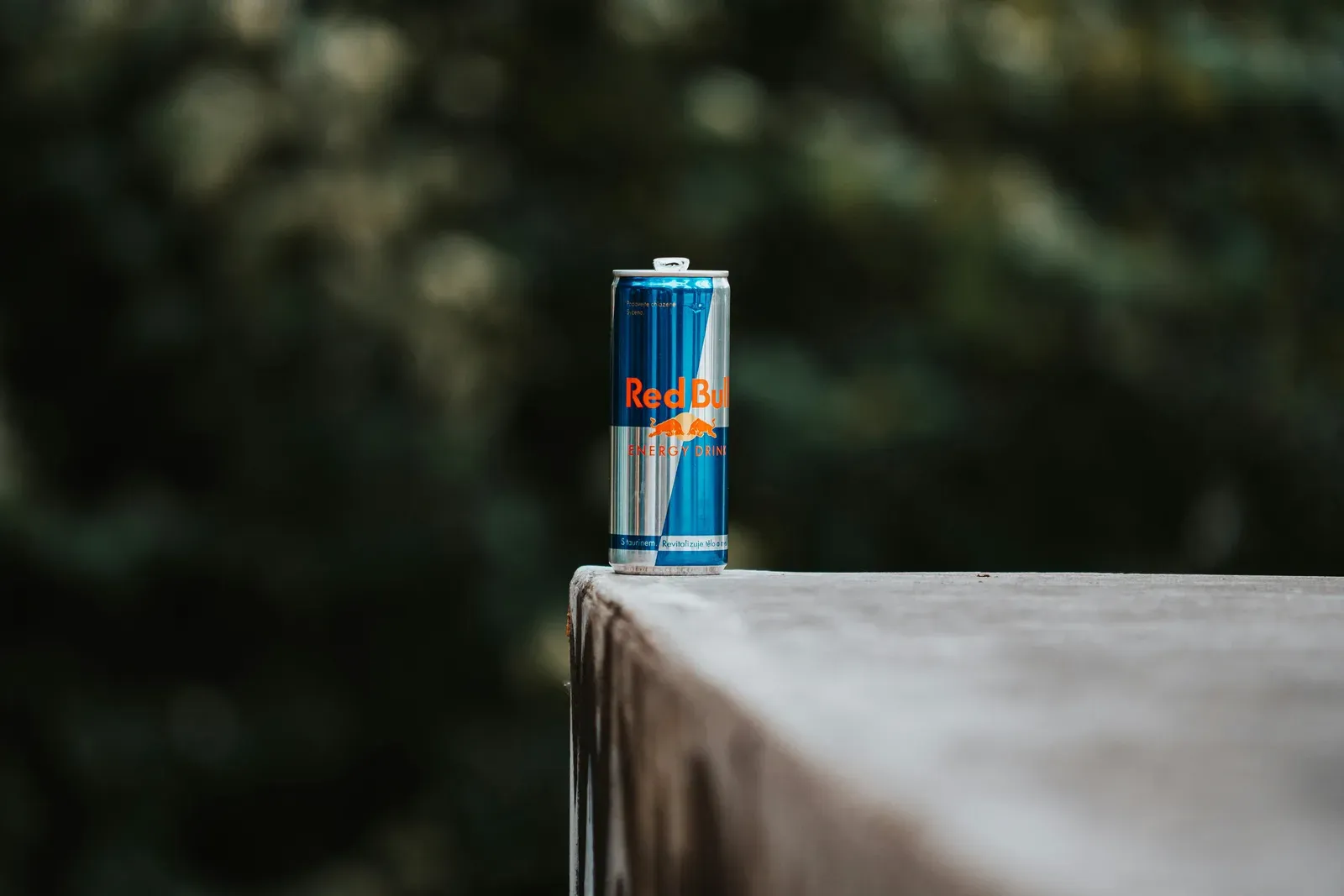 A can of Red Bull on the edge of a table.